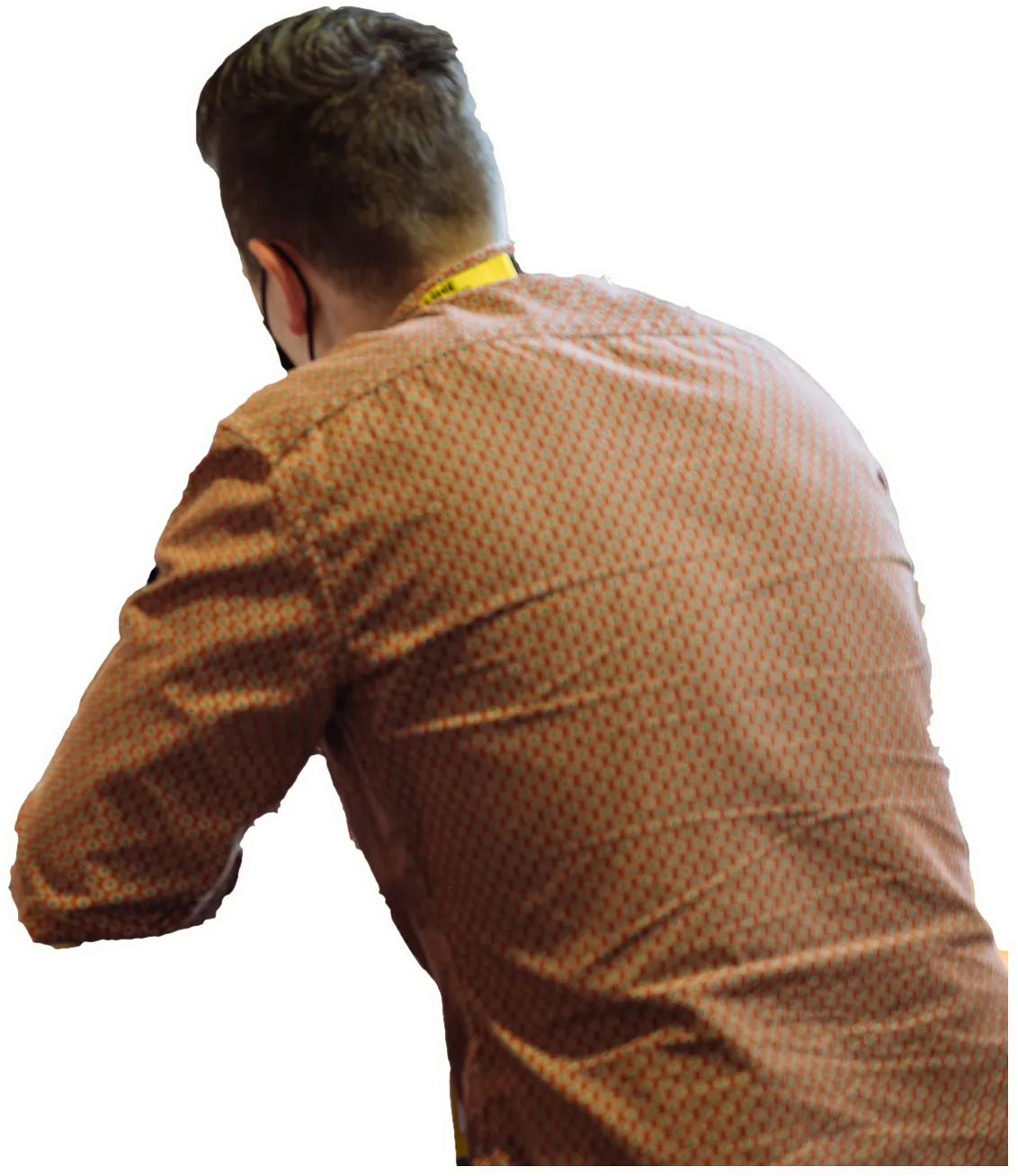 Vu de dos, son interlocuteur en chemise, accoudé à la table.