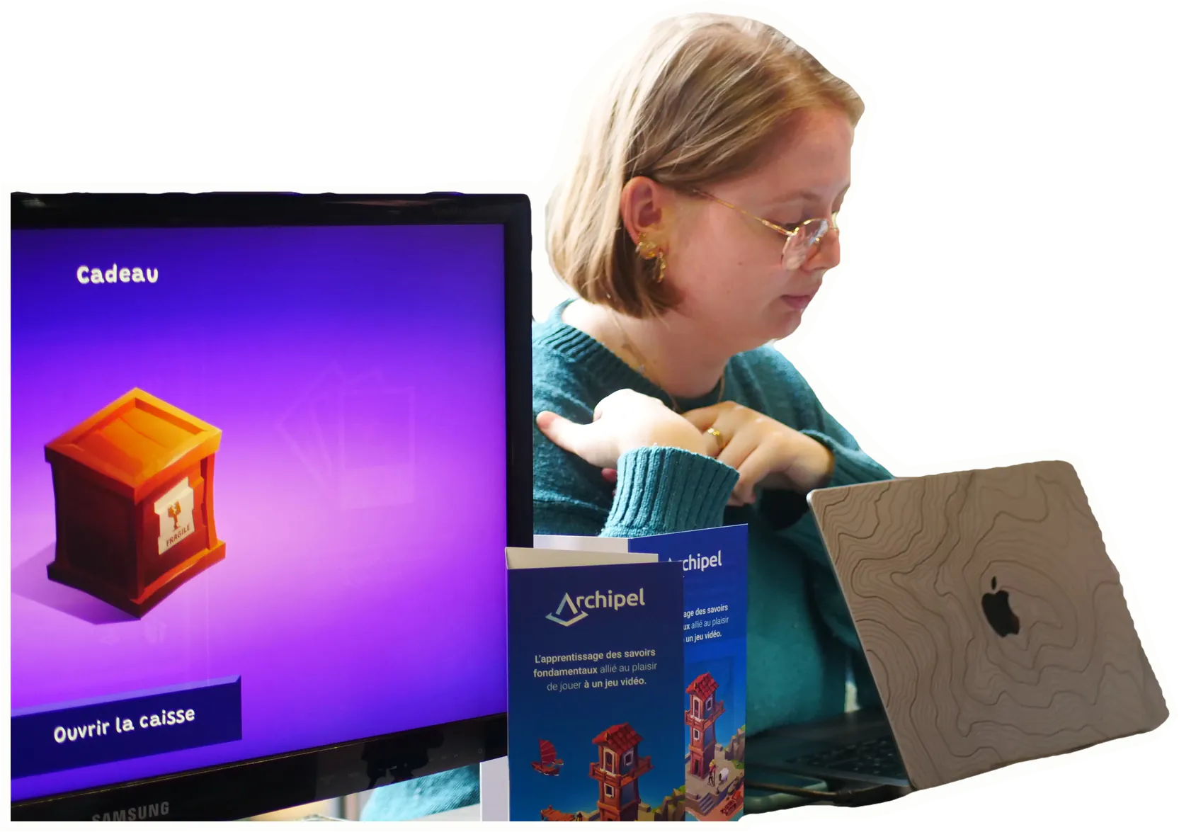Sur un stand, une personne devant son ordinateur portable, à côté de l’écran d’un jeu.