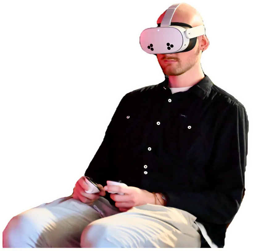 Un visiteur assis, casque de réalité virtuelle sur les yeux, les manettes en main.