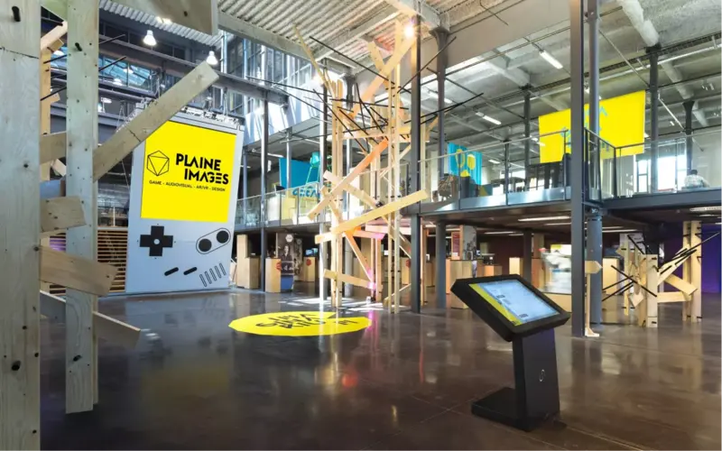 L’Imaginarium : charpentes de bois, grande verrière et affiche jaune Plaine Images.