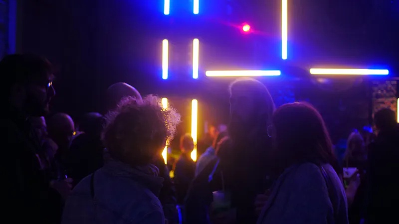 La foule de PIX Night sous des tubes lumineux bleus et jaunes.