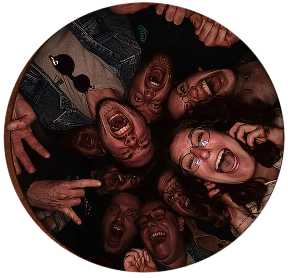 Vue d’en bas, un cercle de participants hilares crie dans l’objectif du photobooth.