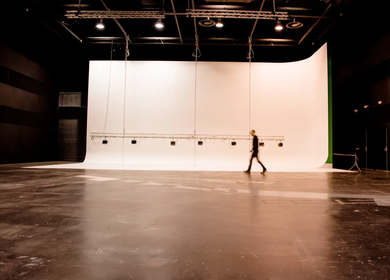 Le grand fond blanc du studio de tournage de 500 m², qu’une personne traverse.